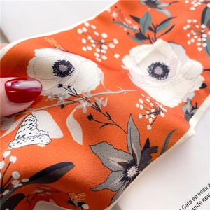 Macro detail of silk scarf necklace featuring orange floral patterns and smooth texture