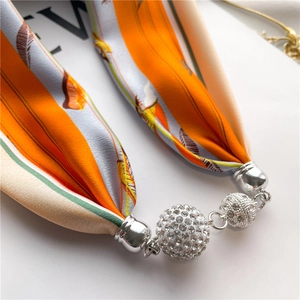 Detailed close-up of a satin scarf necklace with crystal-encrusted sphere pendants