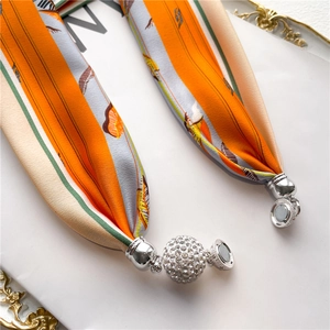 Macro detail of silk scarf necklace featuring magnetic silver clasp and crystal pavé ball