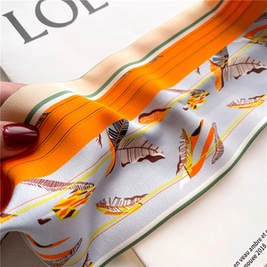 Detailed view of orange striped silk twilly scarf featuring elegant feather print patterns