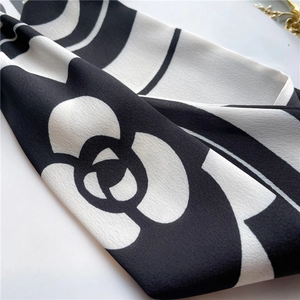 Macro detail of silk scarf with camellia flower print and elegant black-white pattern
