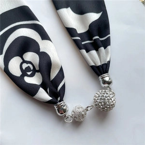 Close-up of silk scarf necklace with camellia print and sparkling diamond ball pendants