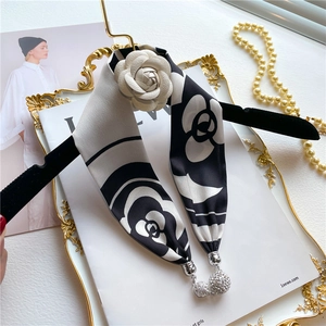 Detail of silk twilly scarf necklace with camellia flower and crystal pendant on tray