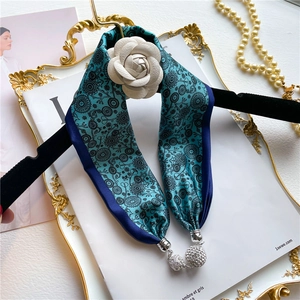 Écharpe en soie florale avec camélia blanc et pendentif strass sur plateau chic