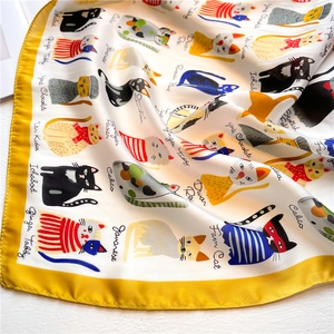 Close-up of silk scarf showing cartoon cat illustrations with yellow border detail