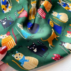 Detailed macro view of dark green silk scarf featuring hand-drawn cat illustrations