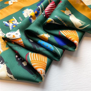 Detailed view of dark green silk scarf featuring hand-drawn farm cat illustrations