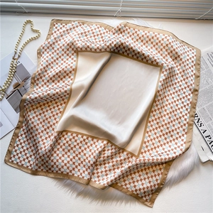 Detail view of square silk scarf with geometric scale pattern in brick red and blue