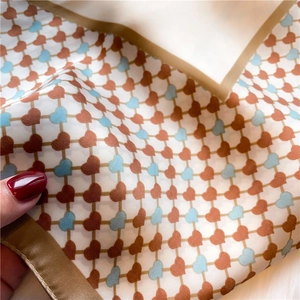 Macro shot of silk scarf detailing brown grid pattern and small hearts with satin edges
