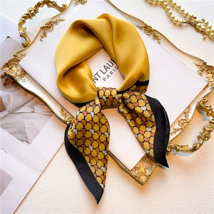 Elegant yellow silk scarf with heart pattern tied in a bow on a luxury tray with pearls