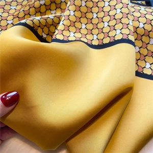 Macro shot of yellow silk scarf with heart patterns and premium satin texture folds