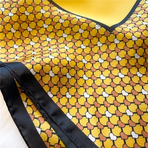 Macro detail of silk scarf featuring colorful heart patterns and black satin borders