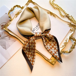 Detailed view of champagne satin silk scarf with orange heart geometric patterns