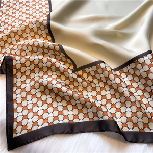Detail of silk square scarf showing soft green panel and orange heart geometric patterns