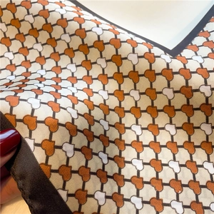 Detailed macro view of the silky satin square scarf with heart patterns and dark brown edges