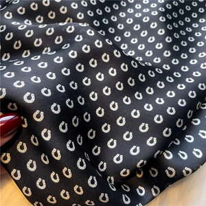 Detailansicht eines schwarzen Seidenschals mit Hufeisenmuster und glatter Textur