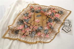 Detailed close-up of a pleated silk scarf with floral prints in yellow and pink hues