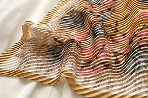Macro detail of pleated silk scarf with vintage floral and rope patterns in gold and pink