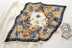 Detailed view of sunburst pleated silk scarf with floral print and navy border detail