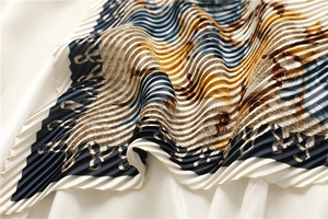 Macro view of pleated silk scarf with luxury chain and rope pattern in navy blue