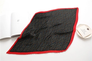 Detail view of red and black pleated scarf with colorful letter H pattern and texture