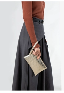 Dettaglio pochette dorata a trama intrecciata con cinturino da polso per donna