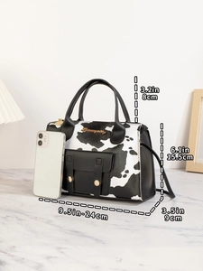 Nahaufnahme der Handtasche mit Kuhmuster, Seitengurt und iPhone zum Größenvergleich