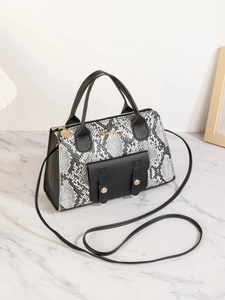 Detailaufnahme der Schlangenhauttextur und des goldenen Logos auf der Damenhandtasche