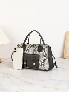 Details der Handtasche mit Steinmuster, Schlangentextur und Handy als Größenreferenz