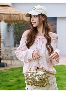 Détail du sac à chaîne à paillettes dorées assorti à une tenue rose à épaules dénudées chic