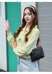 Détail d'un sac à chaîne à paillettes noires avec un sweat-shirt jaune en maille gaufrée