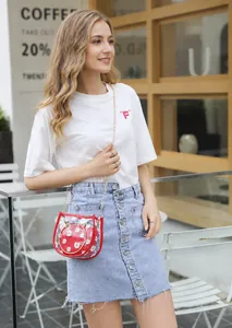 Detail of red transparent PVC crossbody bag with daisy prints and gold chain strap
