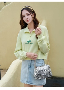 Vue détaillée d'un sac à chaîne à paillettes argentées avec un sweat polo vert gaufre