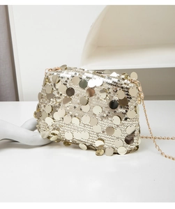 Gros plan d'un sac de soirée à paillettes avec chaîne dorée sur décor blanc minimaliste