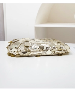 Détail d'une pochette de soirée à paillettes dorées avec des disques métalliques texturés