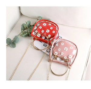 Close-up of mini transparent daisy print handbags with golden metal handles and chain straps