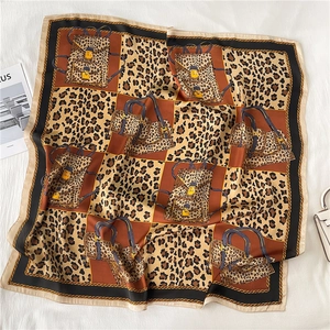 Detail of silk-like leopard print square scarf featuring handbags and golden chain motifs