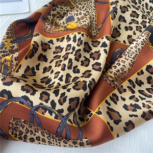 Detail of leopard print and geometric patterns on emerald silk scarf fabric texture