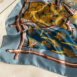 Detailed texture of blue-grey silk scarf with golden bamboo and feather floral prints