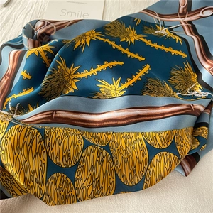 Detailed close-up of an emerald green satin square scarf with artistic floral prints