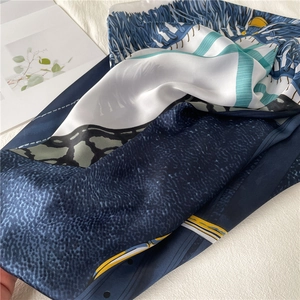 Close-up of emerald silk scarf with leopard print and artistic patterns on white background