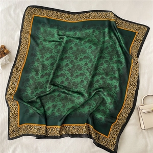 Close-up of emerald green silk scarf featuring leopard print borders and floral patterns