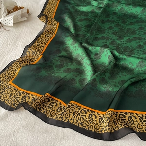 Detail of emerald green silk scarf featuring rose prints and leopard pattern borders