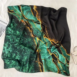 Detailed texture of emerald silk scarf with golden marble patterns and luxury accessories