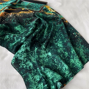Detail of emerald green silk scarf with artistic abstract marble and leopard print patterns
