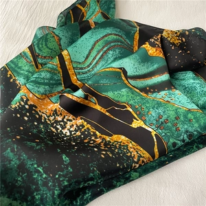 Detail of emerald green marble print silk scarf with luxury satin finish texture