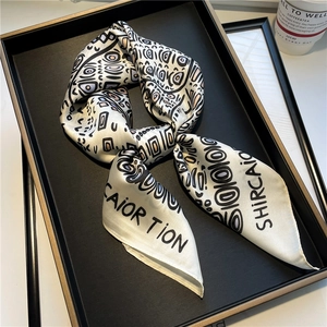 Ethnic style square silk scarf with geometric letter patterns on a black metal tray