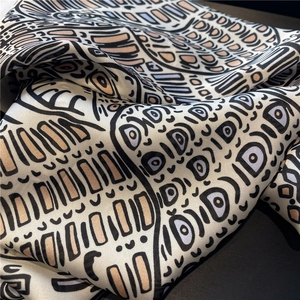 Close-up of silk scarf fabric showing smooth texture and letter D pattern print