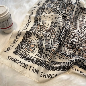 Detail of ethnic geometric print silk scarf displayed on a soft white faux fur rug