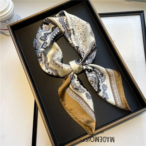 Elegant paisley print silk square scarf tied in a bow on a luxury display tray